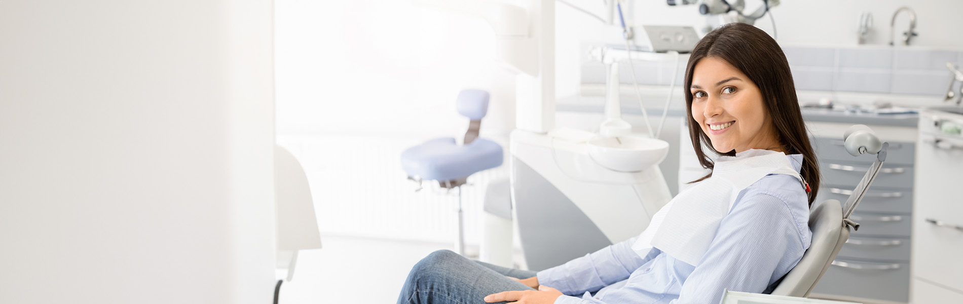 A woman sitting in a dental chair within a dentist s office.