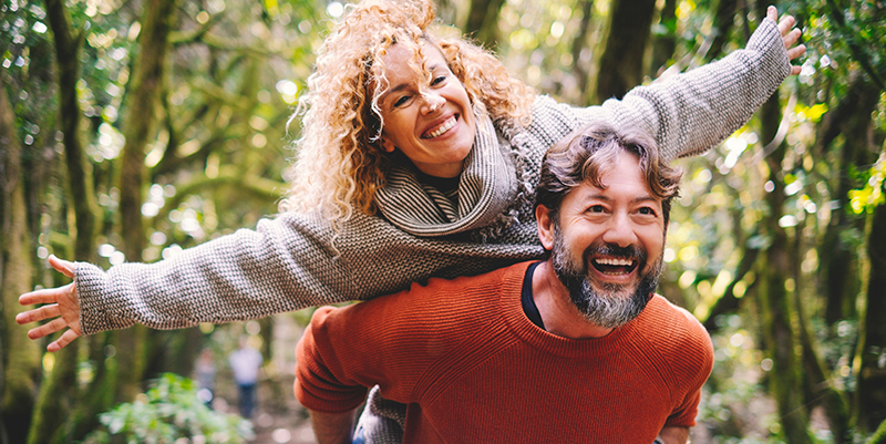 A man and woman are joyfully embracing each other on a hike, with the woman s arms raised in excitement.