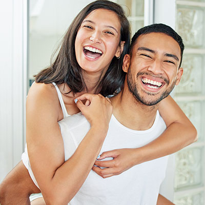 A young man and woman are joyfully embracing each other with smiles on their faces.